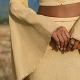 In a sunlit field, a person models AYA Sacred Wear’s Indian Set in Yellow Gold—a cotton two-piece with a flowy bell-sleeve top and maxi skirt. The geometric pattern and breathable fabric give this outfit effortless charm.