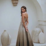 A woman wearing the Boho Top Corset and Skirt Women set by AYA Sacred Wear stands in a minimalist, arched alcove. She is surrounded by textured, neutral-toned pottery, creating an elegant and serene atmosphere.