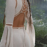 In a misty green forest, a woman wears the Mandara Dress in Ivory by AYA Sacred Wear—an organic boho wedding dress with openwork lace, crisscross lace-up back, linen crinkle fabric, and hand-stitched embroidery for a dreamy, ethereal look.