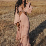 Woman in a pink dress standing in a field with mountains in the background