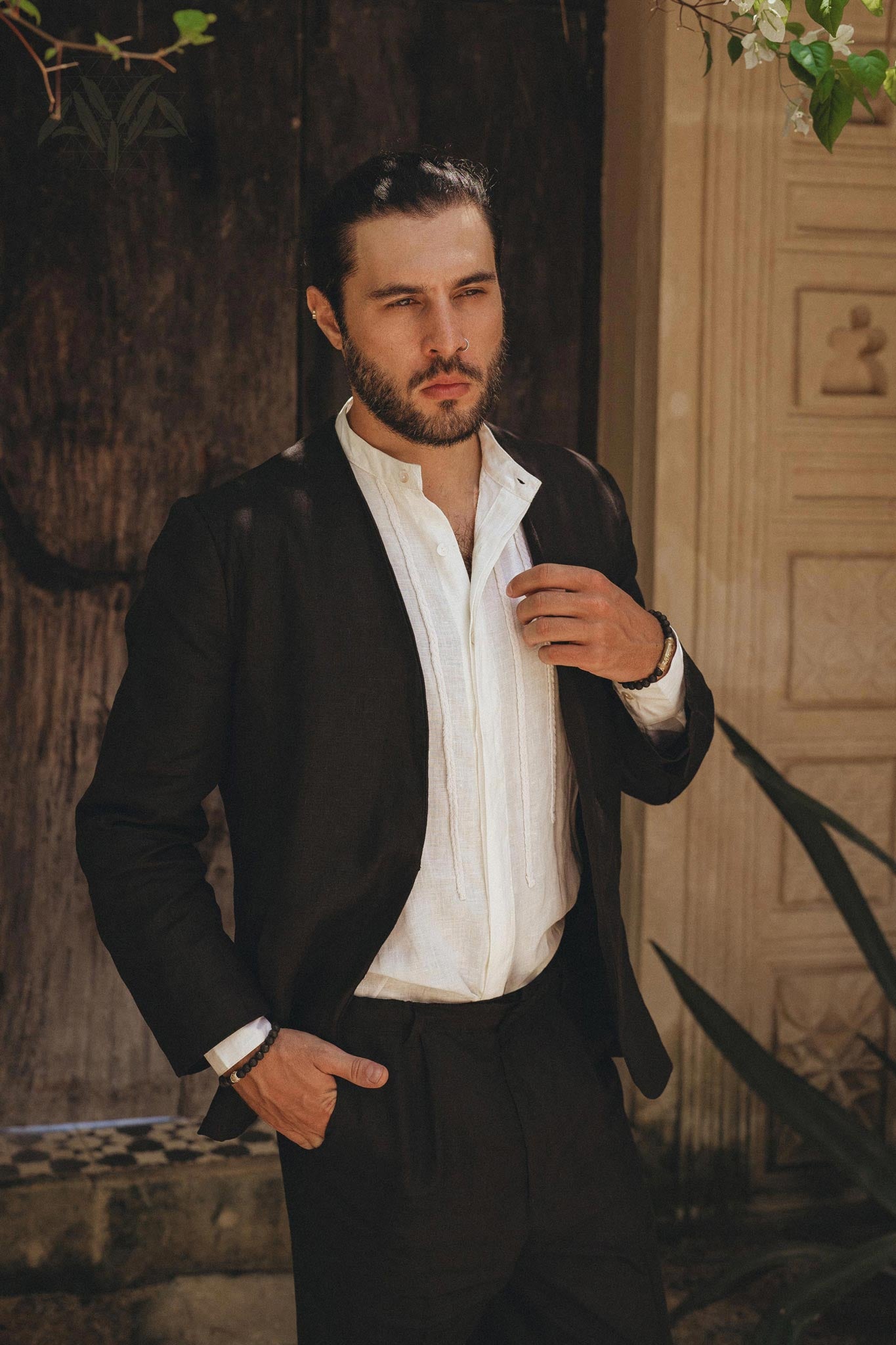 Male model with a top knot and beard, wearing a fine quality organic black linen blazer jacket over a white shirt