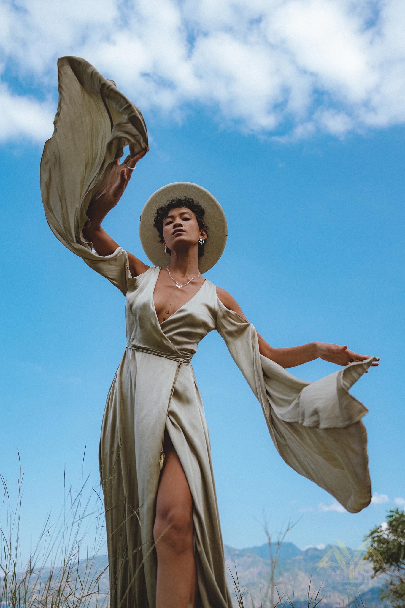 Capture attention with this ethereal light sage goddess dress. A graceful silk creation, perfect for bridesmaids or as a wedding guest dress. Be enchanted by its bohemian charm and billowing bell sleeves.