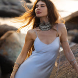 Mist blue peace silk maxi slip dress made from organic Ahimsa silk, soft, breathable, and ethically produced without harming silkworms. This bohemian gown features delicate handmade brass angel wing details and a flowing silhouette that flatters the body. Lightweight and airy, it is perfect for summer, travel, ceremonies, weddings, or everyday luxury wear. Botanically dyed with natural pigments, each dress is unique, sustainable, and designed for comfort, elegance, and timeless feminine style.