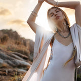 Mist blue peace silk maxi slip dress made from organic Ahimsa silk, soft, breathable, and ethically produced without harming silkworms. This bohemian gown features delicate handmade brass angel wing details and a flowing silhouette that flatters the body. Lightweight and airy, it is perfect for summer, travel, ceremonies, weddings, or everyday luxury wear. Botanically dyed with natural pigments, each dress is unique, sustainable, and designed for comfort, elegance, and timeless feminine style.
