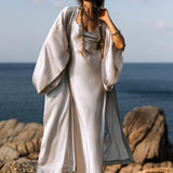 Indulge in the timeless elegance of the Silk Kimono in Mist Blue, a luxurious floor-length robe that combines both style and comfort. Crafted from premium silk, this kimono glides effortlessly over the body, capturing the light with a soft, radiant golden sheen. Its flowing, relaxed silhouette offers an effortlessly chic look, perfect for adding a touch of elegance to any outfit.