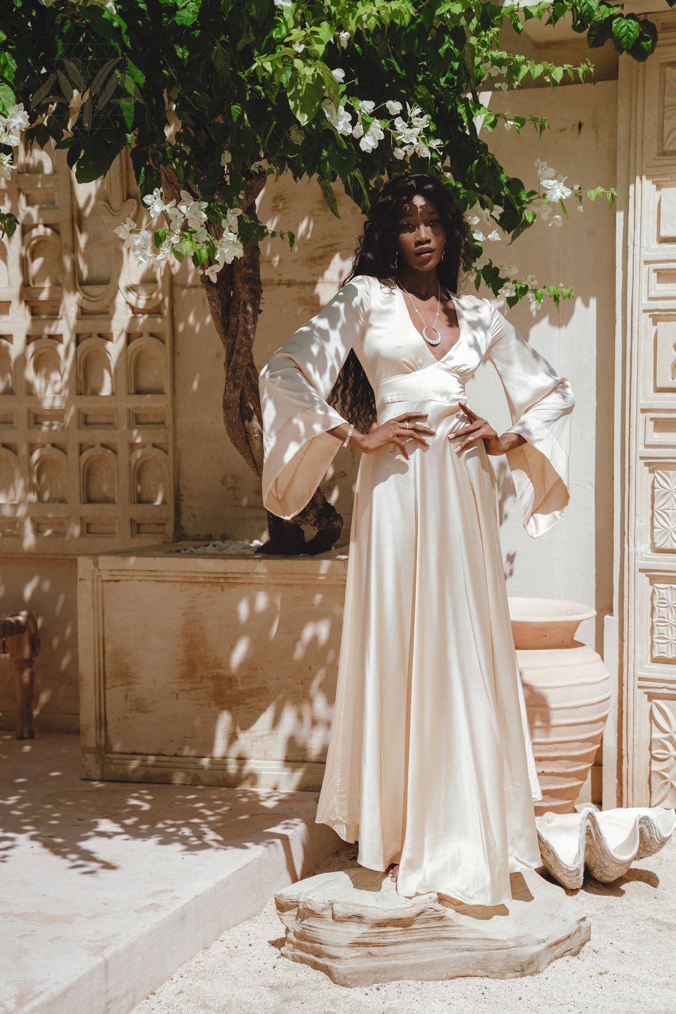 Capture attention in this fairy tale-inspired off-white silk dress, accentuated by bell sleeves and an open back design, perfect for a boho-chic bride.