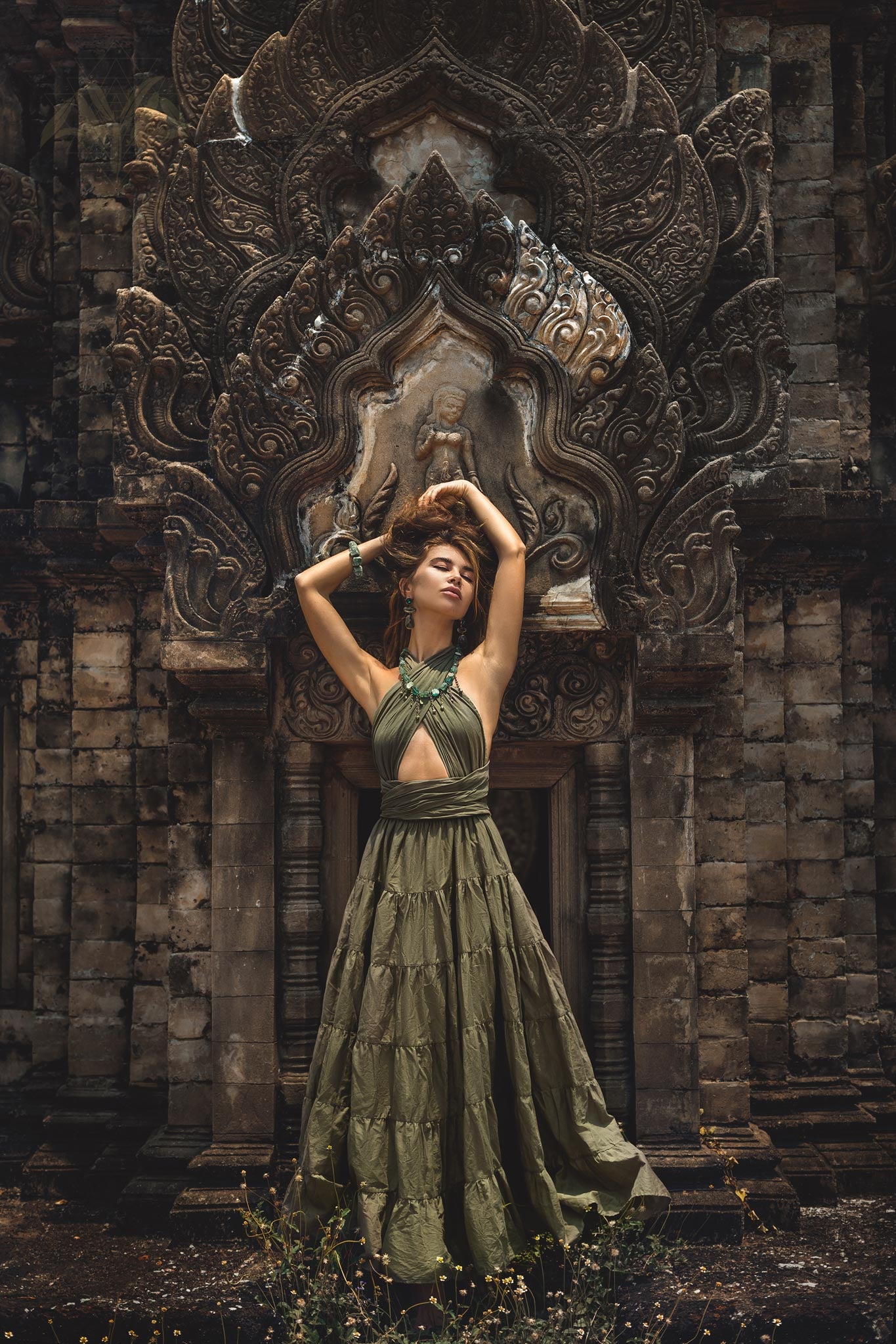 Full length view of woman posing in a dark green organic cotton boho gown in front of a stone temple entrance.